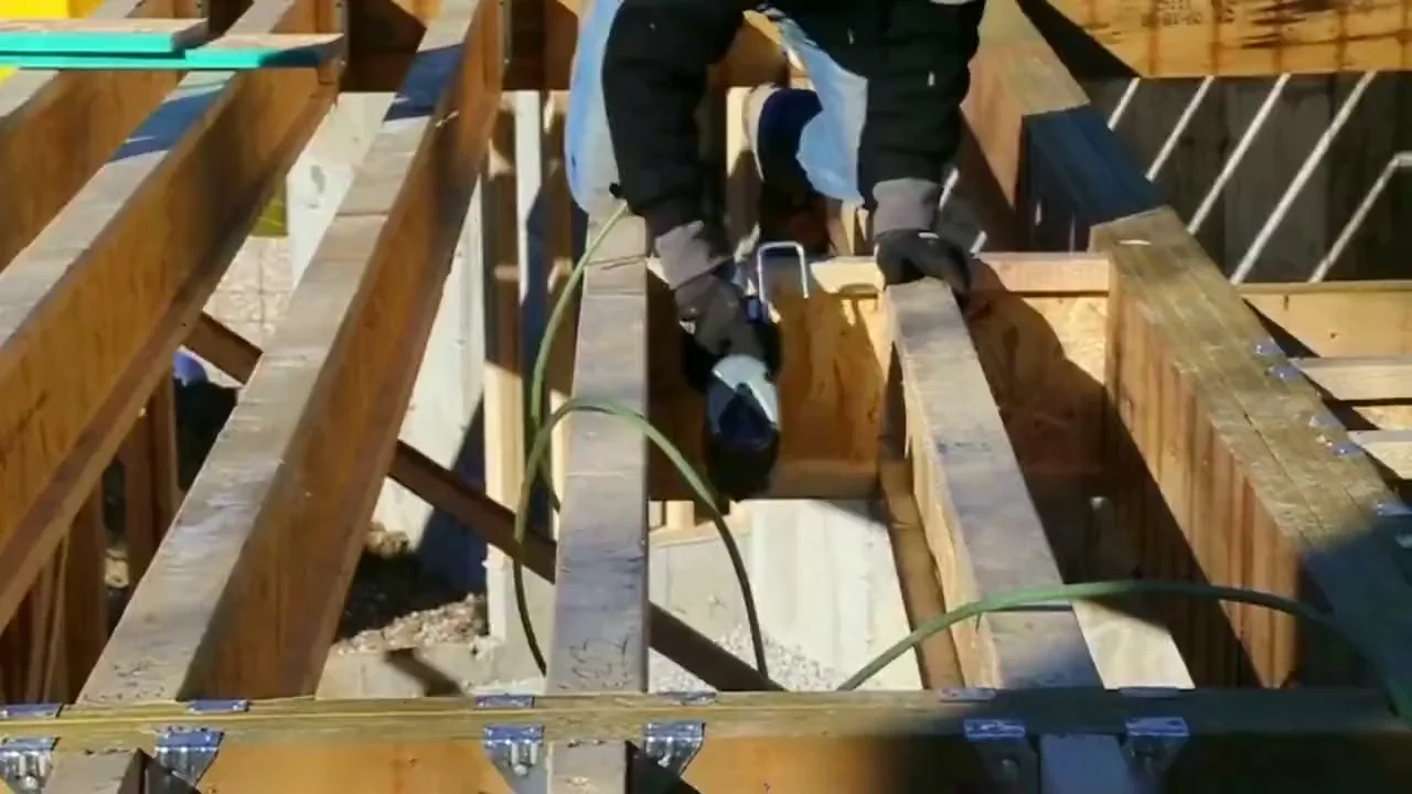 Worker installing wood floor joists on a residential framing project