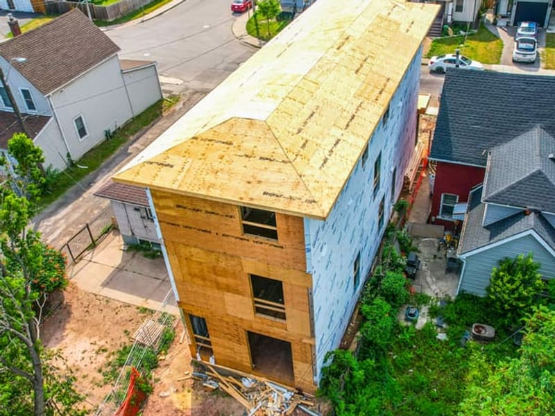 Aerial rear view of multiplex showing roof sheathing and housewrap on residential lot