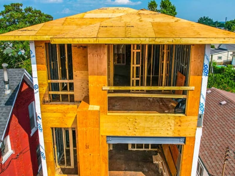 Close-up of top floor wood framing showing roof sheathing and window openings