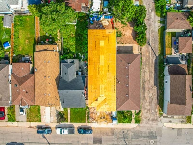 Aerial top-down view of multiplex construction showing new framing among existing homes