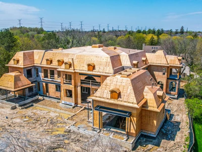 Aerial view of 20,000 sq ft custom estate during wood framing showing complex roof structure