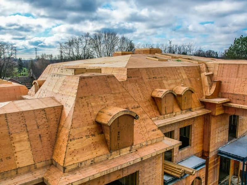 Aerial close-up of custom home roof framing with dormers and OSB sheathing in Markham