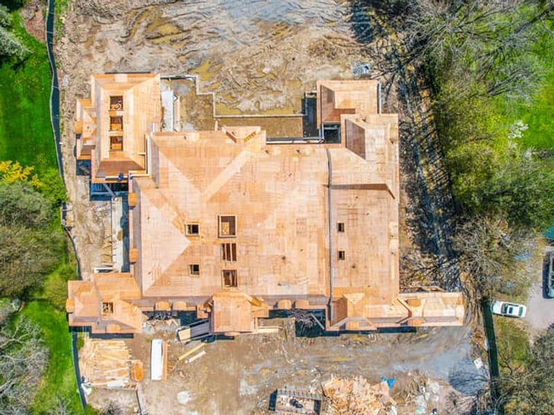 Overhead drone view of custom home roof framing showing complex layout and dormers