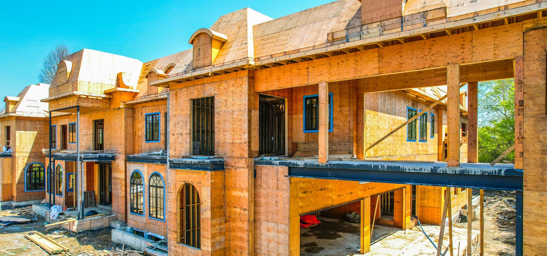 Front facade of luxury custom home under construction with wood framing and steel beams