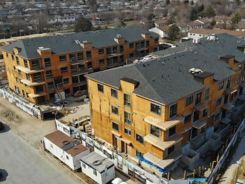 Aerial view of townhouse blocks under construction with wood framing and shingle roofs in Toronto
