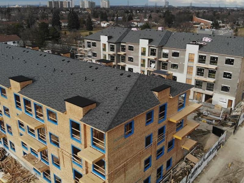Aerial view of two townhouse blocks at different stages with completed cladding and wood framing