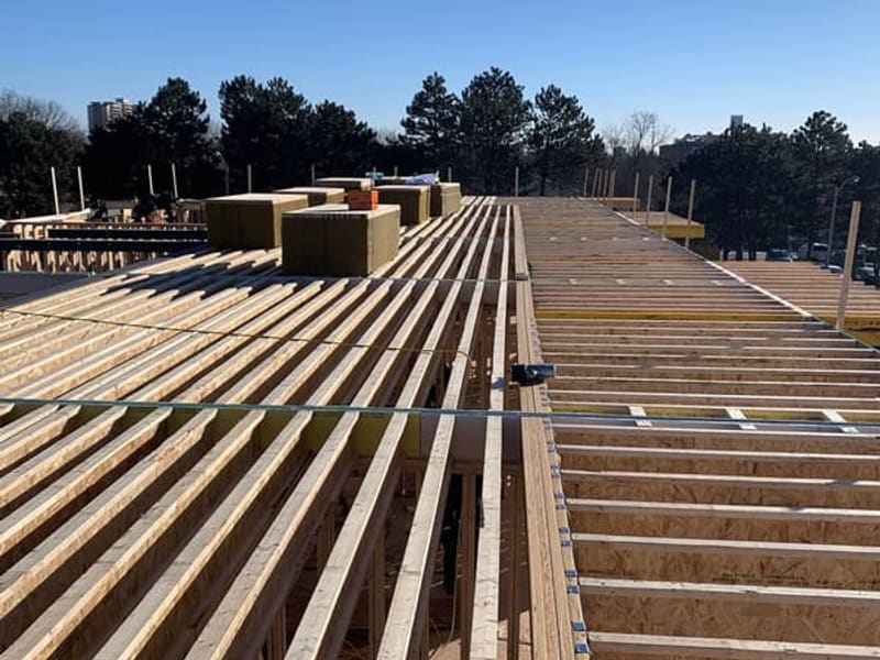 Roof-level view of engineered I-joists and steel beams with rigid insulation on townhouse block