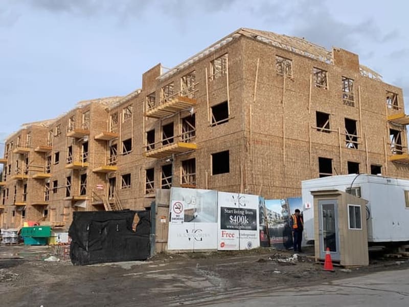 Three-storey townhouse block during active wood framing with OSB sheathing and balcony construction