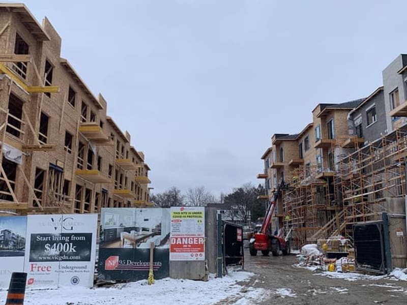 Winter construction site between two townhouse blocks with telehandler crane and scaffolding