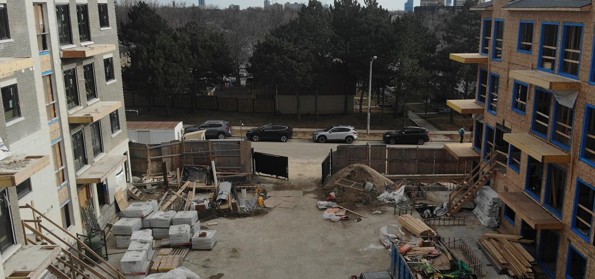 Construction site between two townhouse blocks showing wood framing and building materials in Toronto