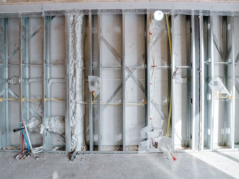Metal stud wall with fire-rated sheathing, spray foam insulation on pipes, and electrical rough-in