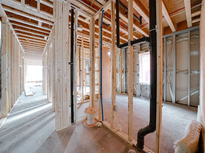 Interior wood framing with plumbing stacks and hallway layout in multiplex unit