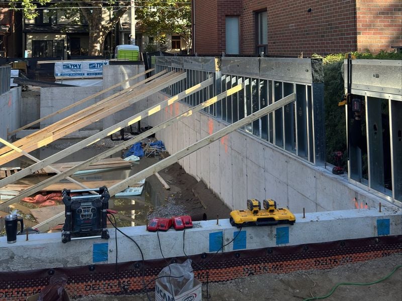 Foundation-level metal stud framing and wood beams at early construction stage