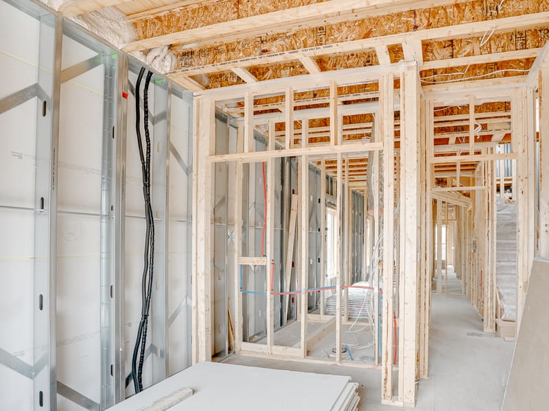 Interior framing showing metal stud partition walls with electrical wiring and plumbing runs
