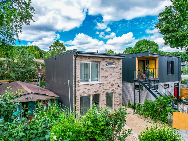 Rear view of completed garden suite with brick and metal cladding and exterior staircase