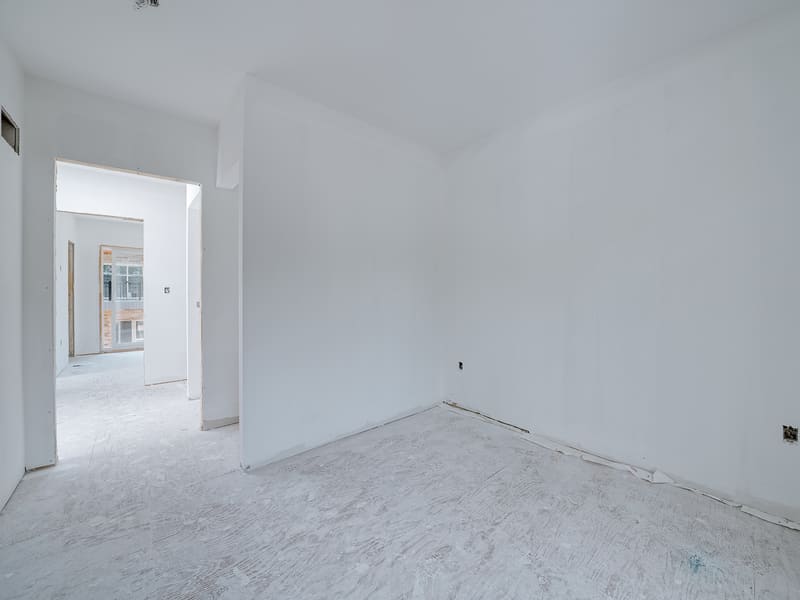Completed drywall room showing smooth finish ready for paint in multiplex unit