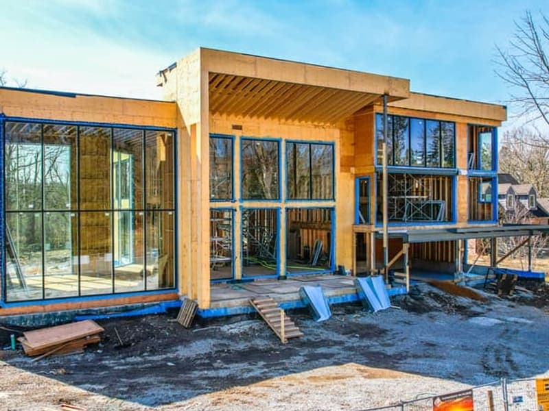 Front facade of modern custom home with floor-to-ceiling glass windows and wood framing