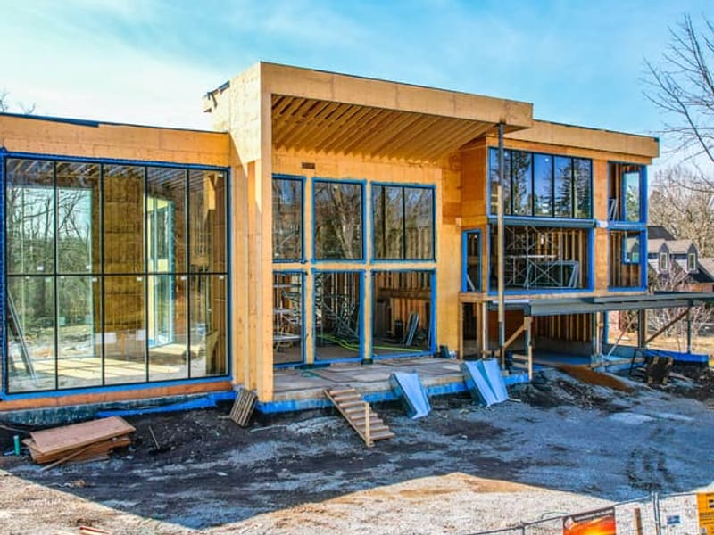 Front facade of modern custom home with floor-to-ceiling glass windows and wood framing