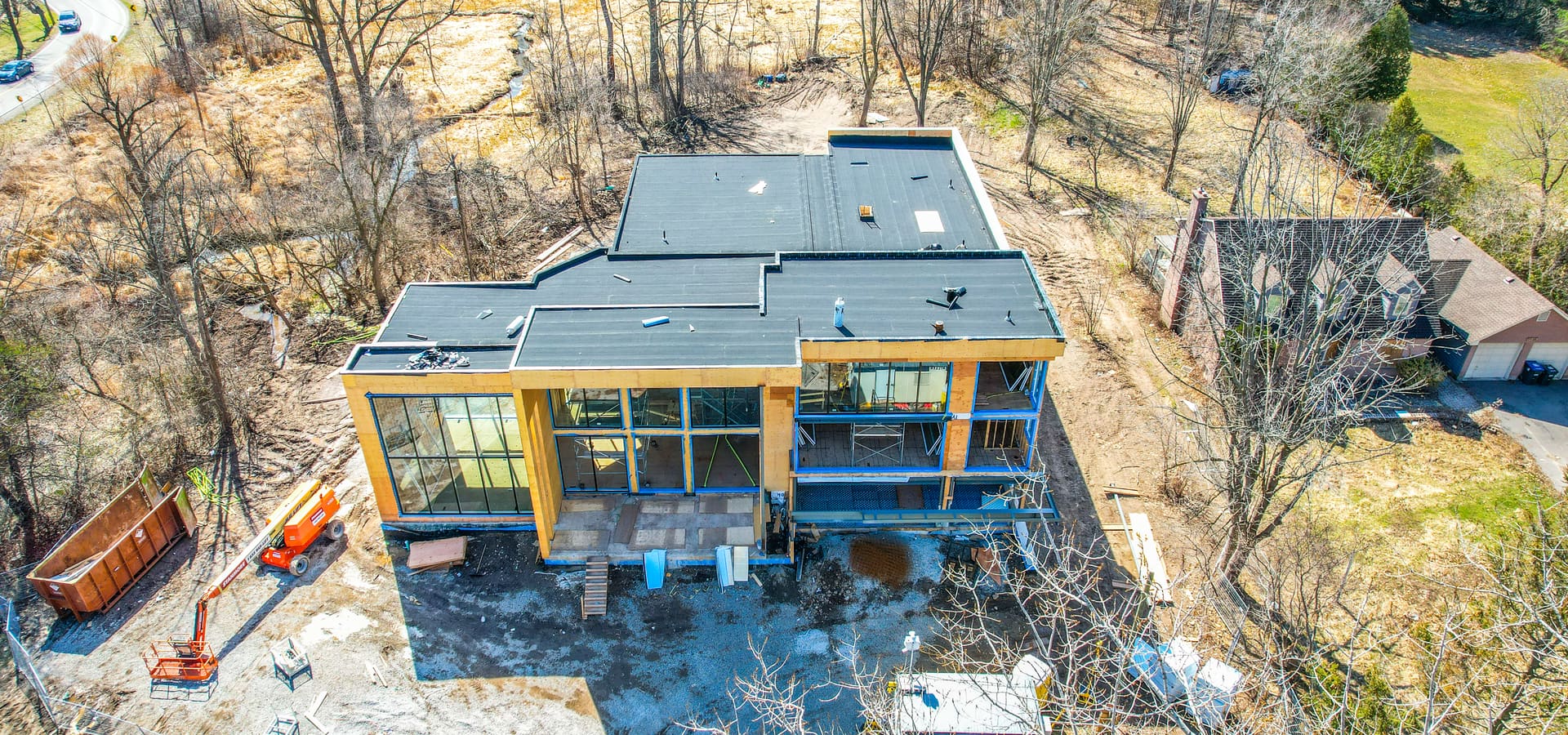 Aerial view of modern custom home during construction showing flat roof and large window openings in Brampton