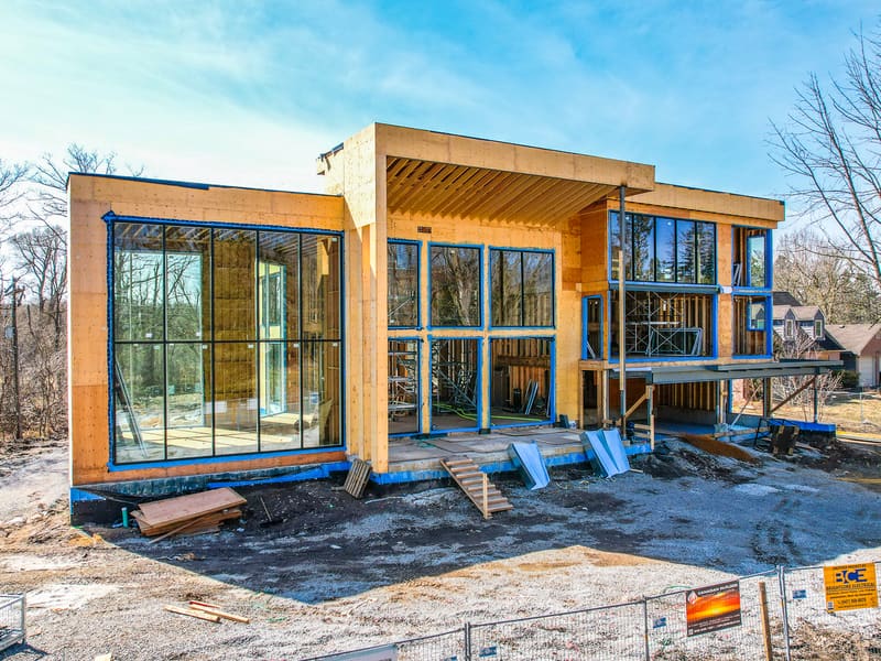 Modern custom home with floor-to-ceiling windows and wood framing during construction in Brampton
