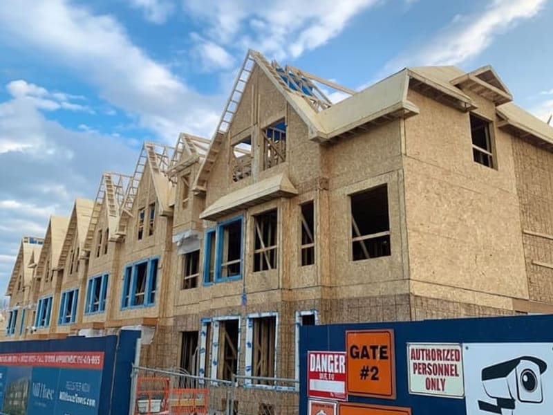Close-up of townhome facade showing wood framing with OSB sheathing and metal roof trusses