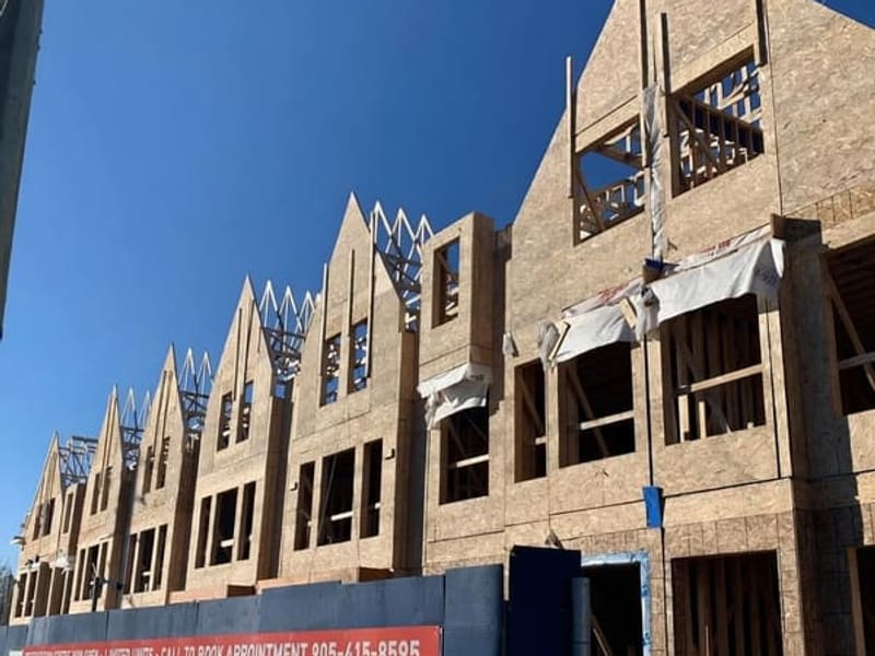 Townhome block with completed wood framing, OSB sheathing, and peaked gable roofs