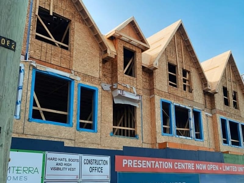 Front elevation of townhome with wood framing, dormer windows, and blue housewrap details